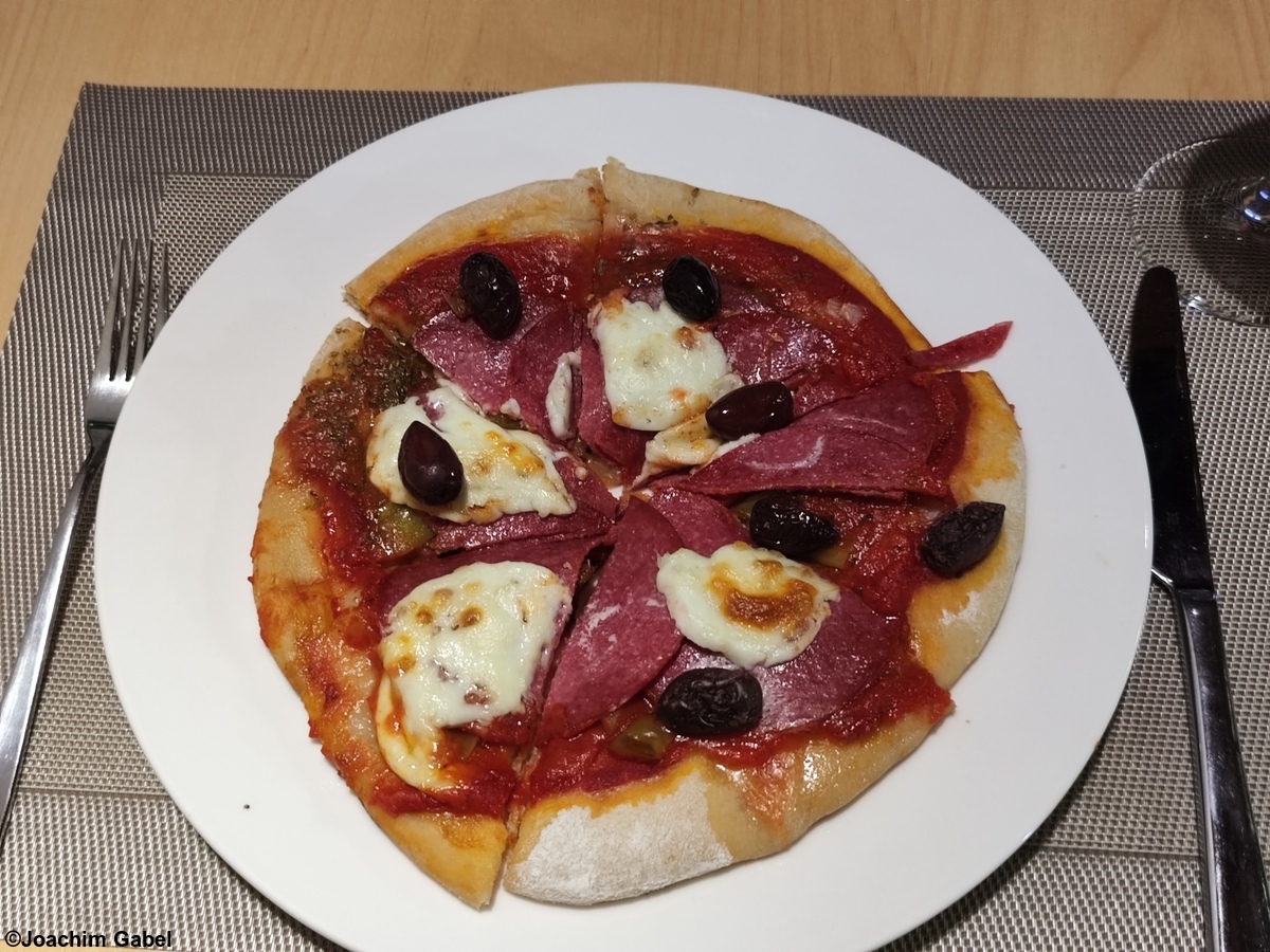 Red pizza with salami, peperoni and olives.Rote Pizza mit Salami, Peperoni und Oliven.