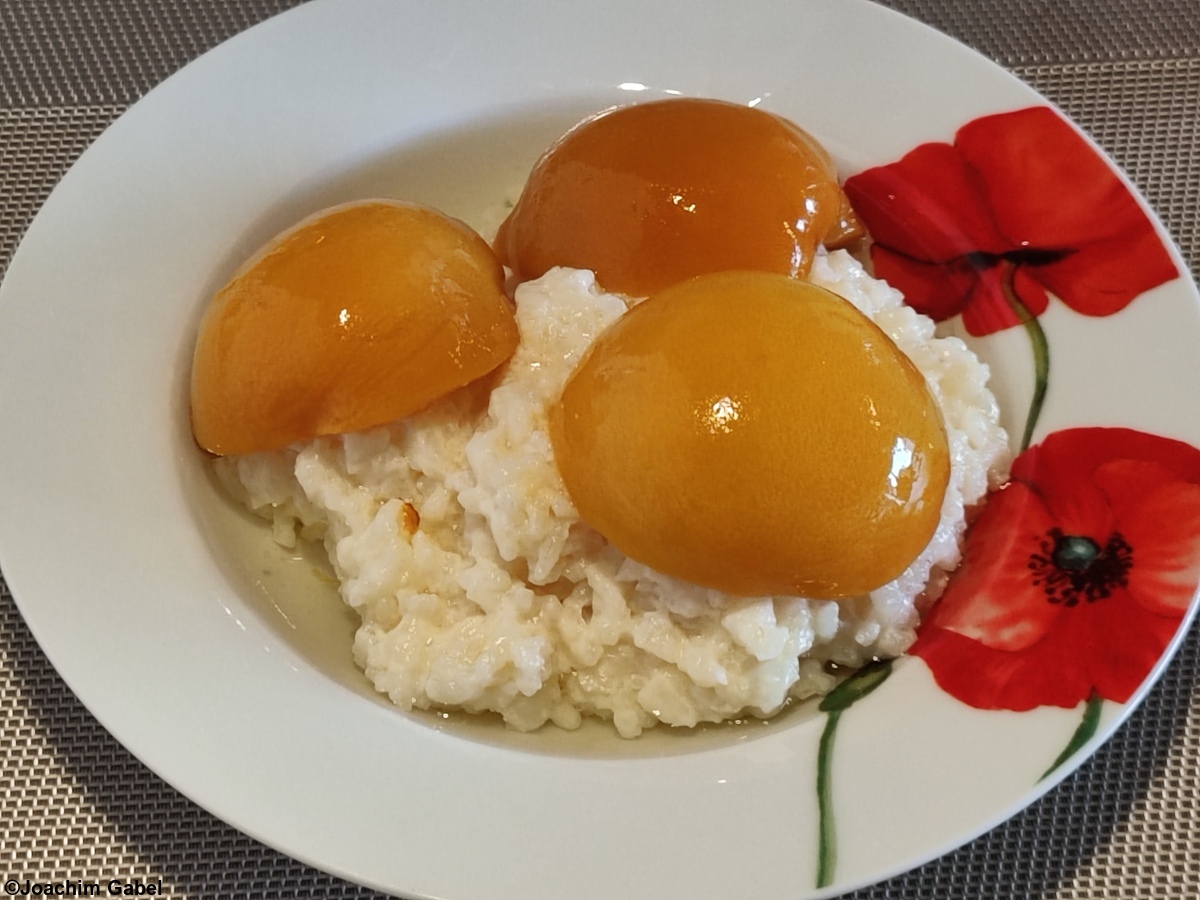 Rice pudding with preserved peach halves.Milchreis mit konservierten Pfirsichhälften.