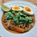 Laksa decorated with cilantro, boiled egg and lime. Laksa dekoriert mit Korianderkraut, gekochtem Ei und Limette.