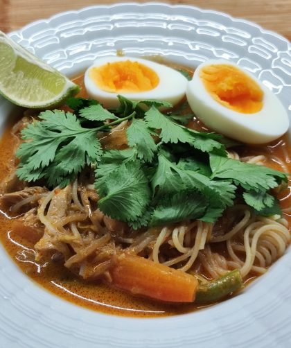 Laksa decorated with cilantro, boiled egg and lime. Laksa dekoriert mit Korianderkraut, gekochtem Ei und Limette.