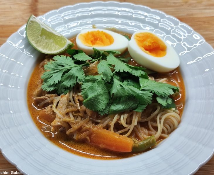 Laksa decorated with cilantro, boiled egg and lime. Laksa dekoriert mit Korianderkraut, gekochtem Ei und Limette.