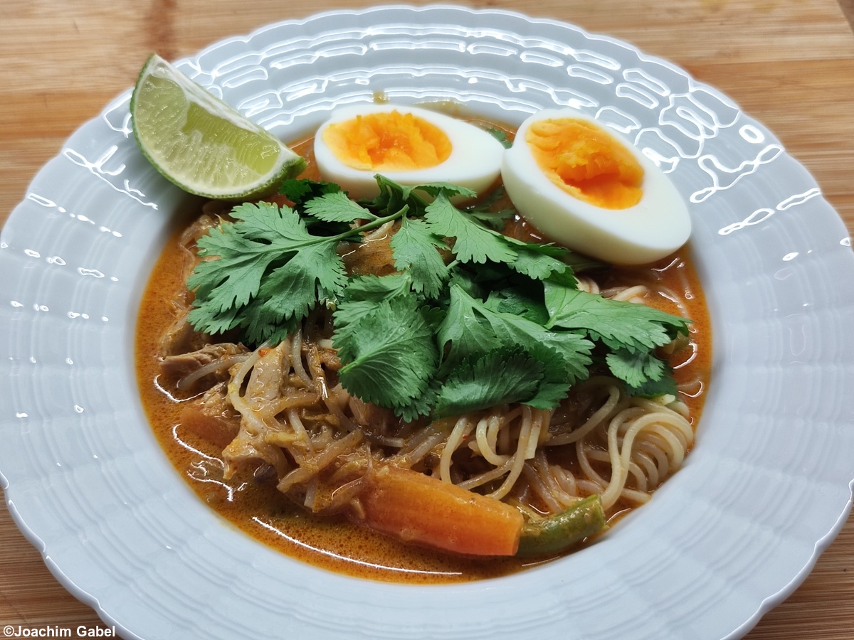 Laksa decorated with cilantro, boiled egg and lime.Laksa dekoriert mit Korianderkraut, gekochtem Ei und Limette.